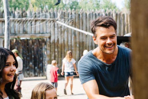 A man and a woman smiling outdoors with people
