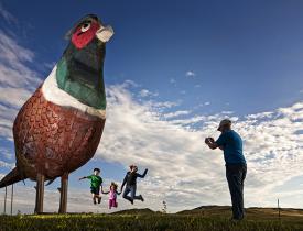 Family jumping in front of the metal pheasnt sculptures